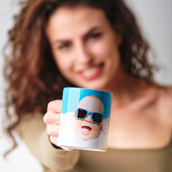 Una persona mostra una tazza personalizzata con una fotografia